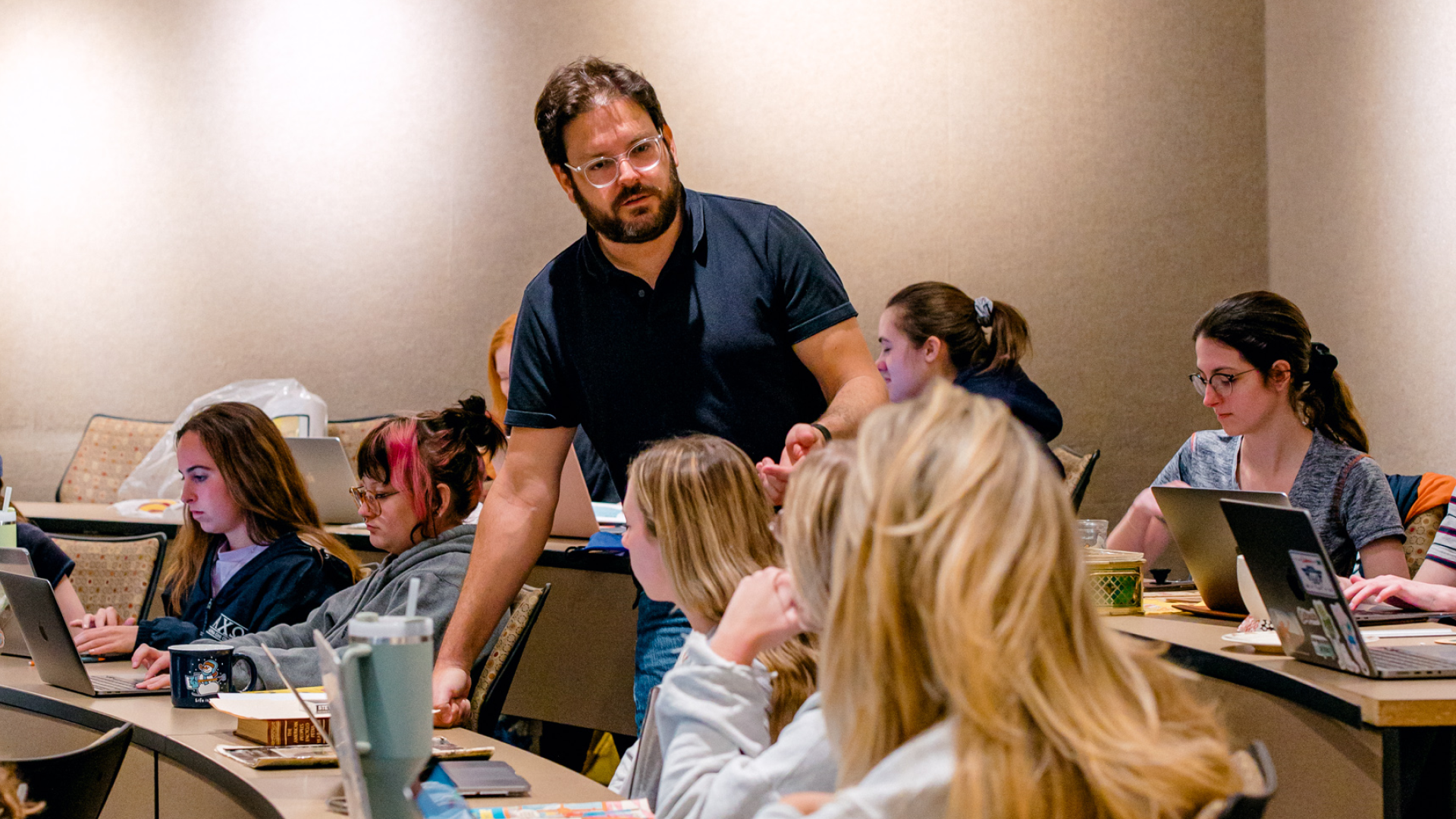 Professor Robert Finkel of Auburn University talking to students with laptops in the middle of a lecture hall